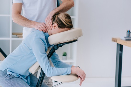 masseur doing seated neck massage for businesswoman
