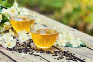 two-cups-of-green-tea-with-jasmine-flowers-on-grunge-wooden-table-outdoors