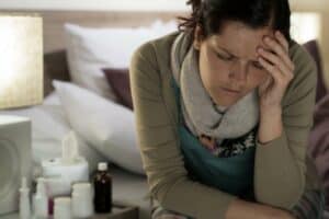 ill-woman-with-medicines-suffering-from-flu-headache-in-bedroom