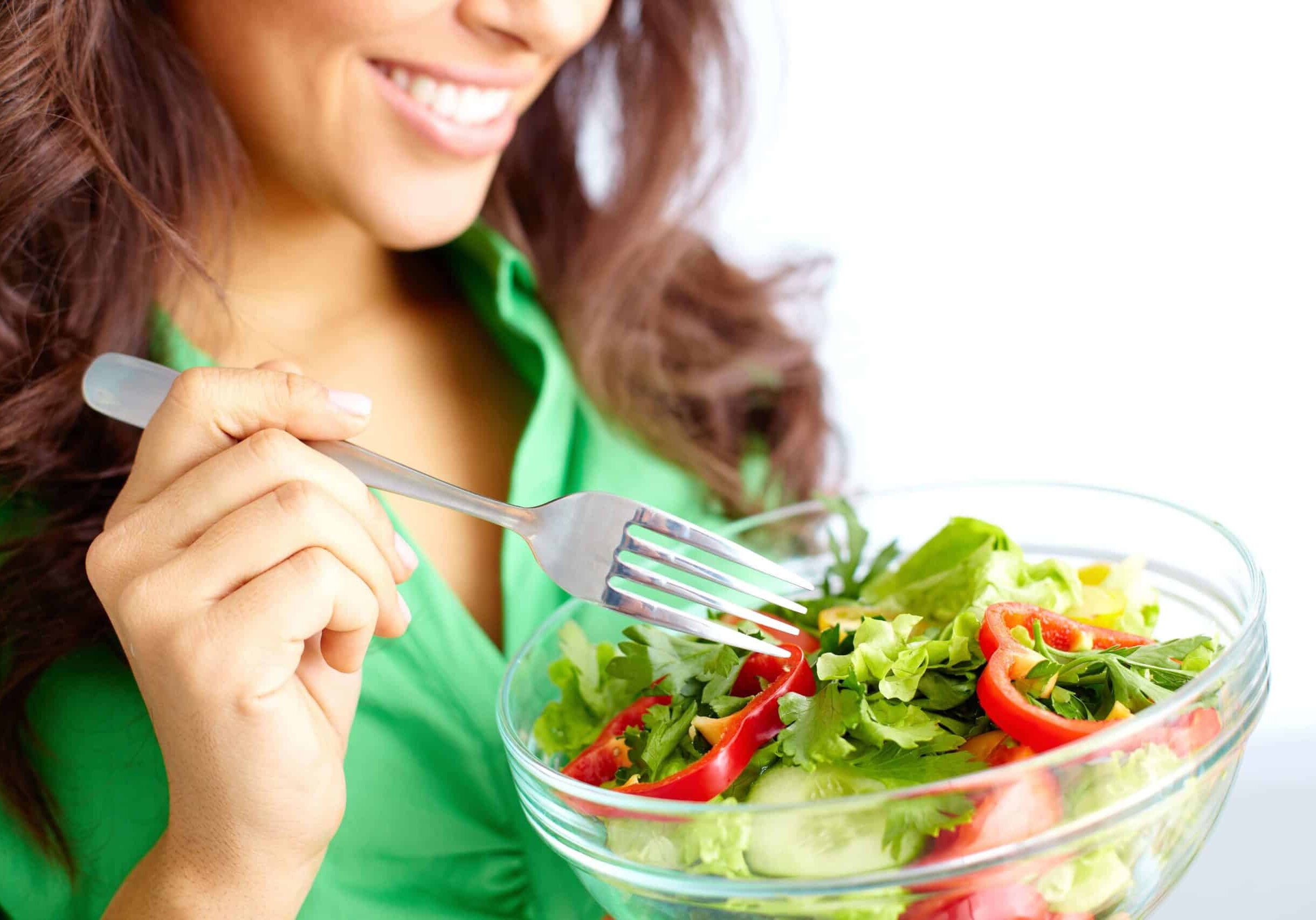 close up of beautiful woman enjoying fresh vegetable salad