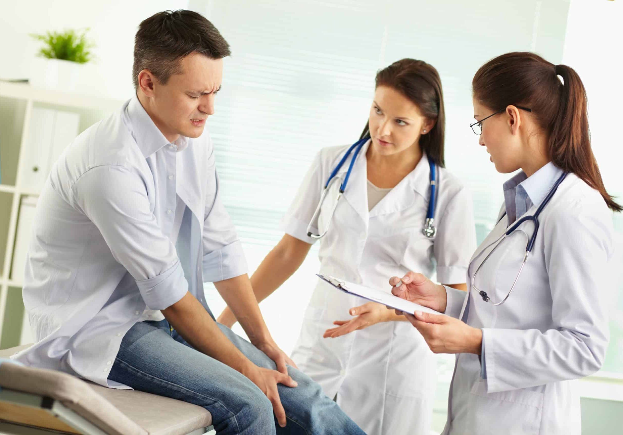 patient-suffering-from-pain-in-the-leg-being-examined-by-a-female-doctor-and-her-assis